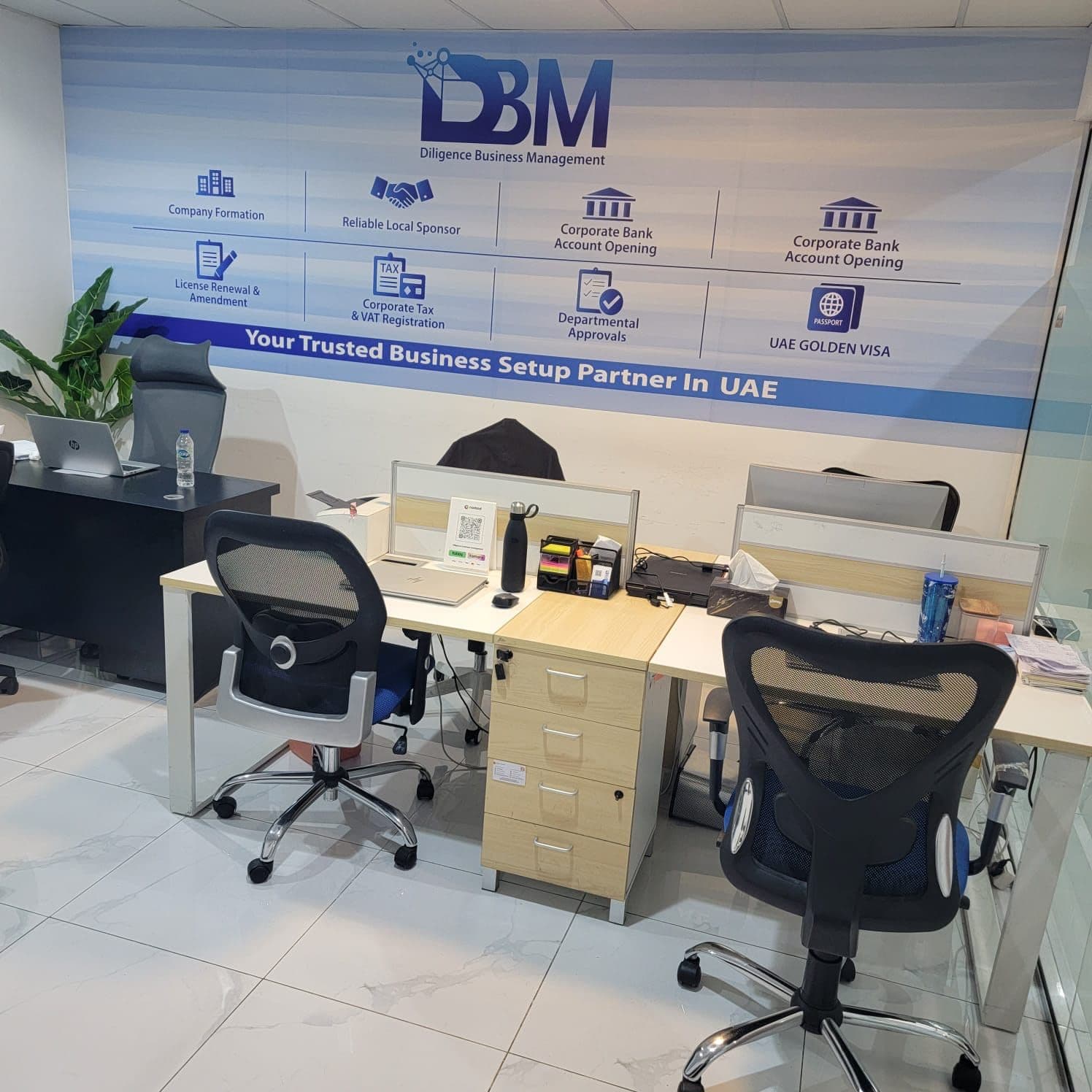 Inside the DBM office at Aspin Commercial Tower, Dubai — branded services wall and team workstations