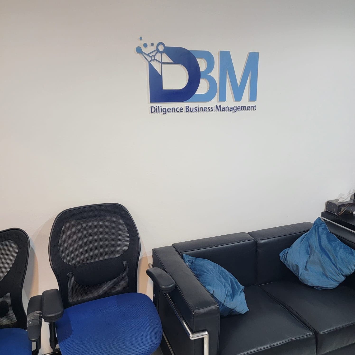 DBM reception area with the Diligence Business Management logo wall and client seating